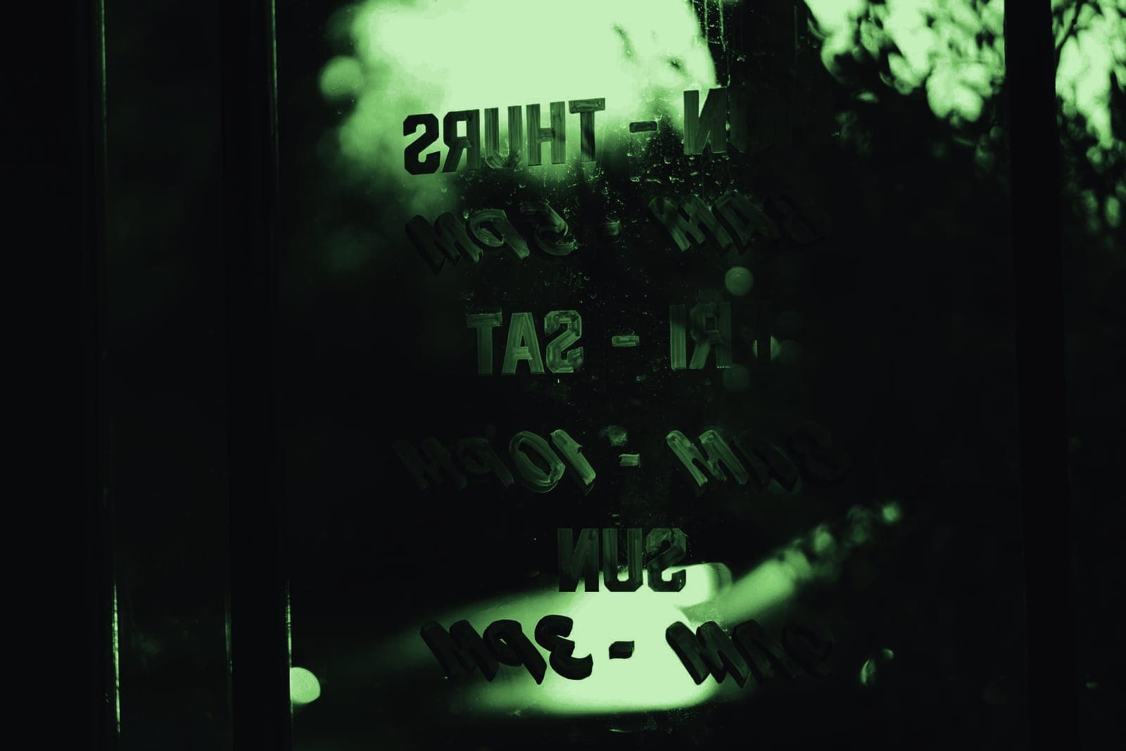 Opening hours lettered on the glass door of a shop