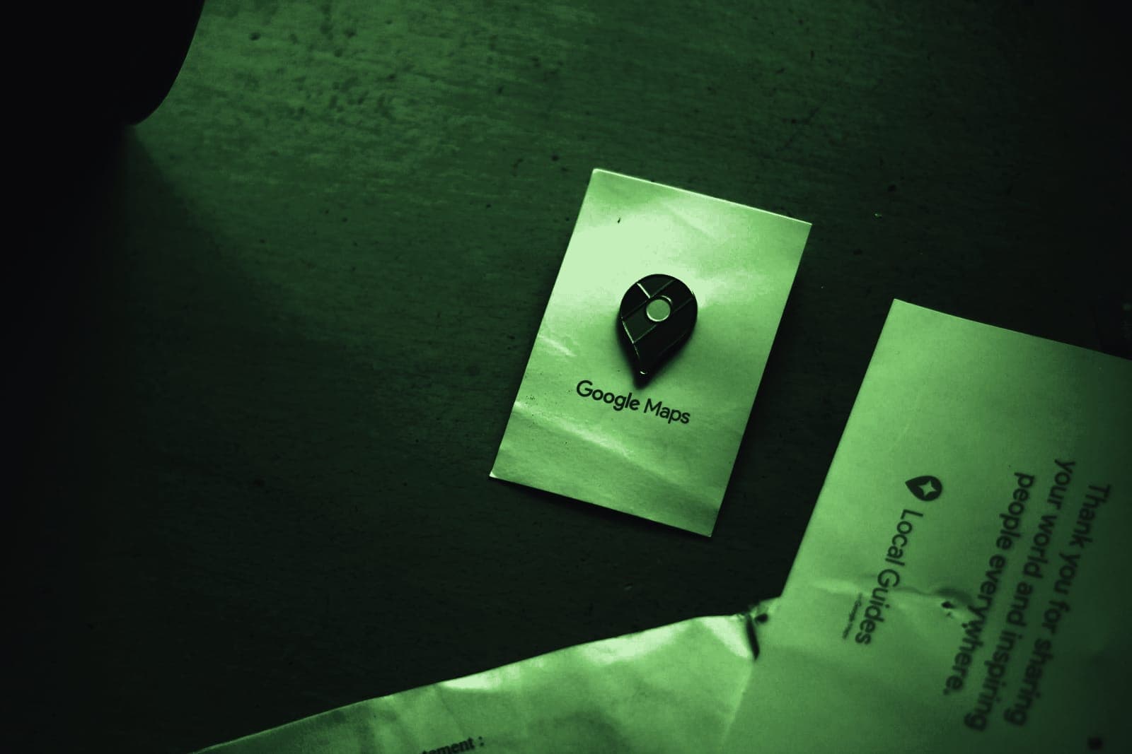 A Google Maps pin printed on a card, lying on a desk