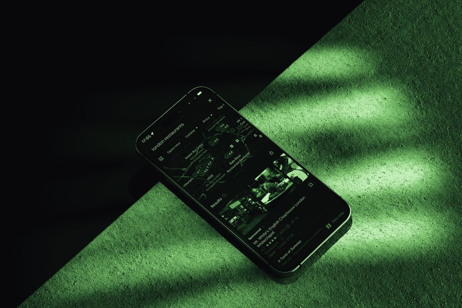 A phone showing a business listing, lit by hard window light